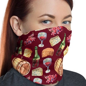 May include: A red face mask with a repeating pattern of wine glasses, grapes, cheese, and wine bottles. The pattern is on a dark red background.