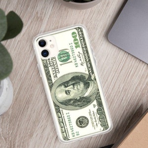 Puede incluir: Una funda transparente para teléfono con un diseño de billete de 100 dólares. El billete presenta un retrato de Benjamin Franklin y el texto "ONE HUNDRED DOLLARS".