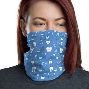 Puede incluir: Una mascarilla facial azul con un patrón de dientes blancos, cepillos de dientes, pasta de dientes e hilo dental. La mascarilla la lleva puesta una persona con el pelo largo y rojo.