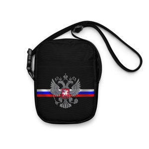 May include: Black crossbody bag with a white, blue, and red Russian flag and the Russian coat of arms in silver.