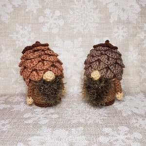 May include: Two crocheted gnome ornaments with brown and tan pine cone hats and brown beards.