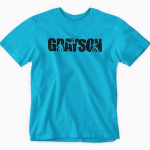 A bright blue t-shirt with the word "GRAYSON" printed on it in a stylized font.