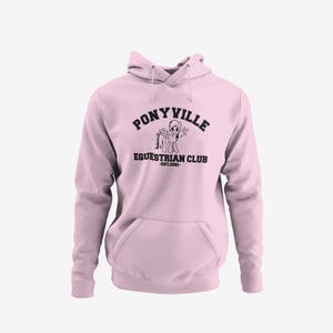 A pink hoodie with the text "PONYVILLE Equestrian Club" printed on it.