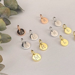 Puede incluir: Una colección de abalorios de iniciales en oro, plata y oro rosa. Los abalorios son redondos y presentan las letras A, E, L, M, N, P, R y S.