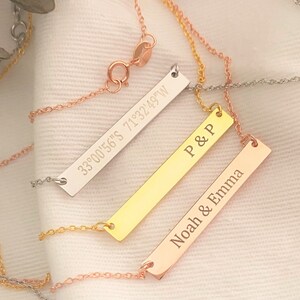 Puede incluir: Tres collares de barra de oro con diferentes grabados. El collar superior tiene las coordenadas "33°00'56"S 71°32'49"W" grabadas en él. El collar del medio tiene "P & P" grabado en él. El collar inferior tiene "Noah & Emma" grabado en él.