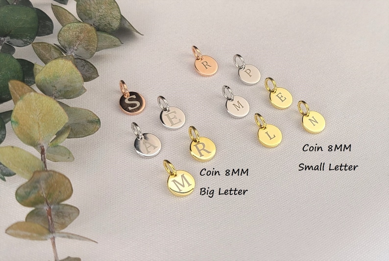 May include: Assortment of 8mm coin charms with different letters engraved in silver, gold, and rose gold. The charms have either a small or large letter engraved on them.  Coin 8MM Small Letter and Coin 8MM Big Letter are written below the charms.