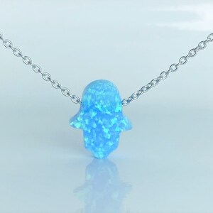 May include: A silver chain necklace with a light blue opal hamsa hand pendant.