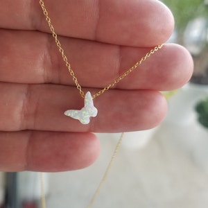 May include: A delicate gold chain necklace with a small white opal butterfly pendant.