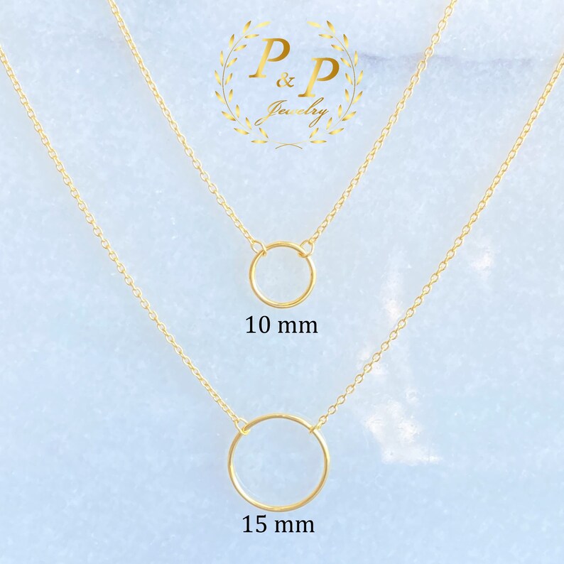 May include: Two gold necklaces with circle pendants. The top necklace has a 10 mm circle pendant and the bottom necklace has a 15 mm circle pendant.  The necklaces are on a light blue background with the text "P&P Jewelry" in a gold wreath.