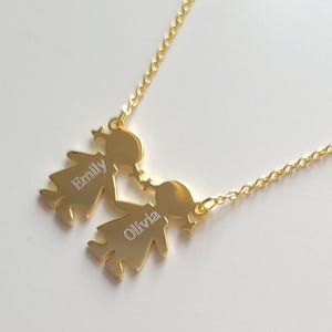 May include: Gold necklace with two figures holding hands. The figures are engraved with the names "Emily" and "Olivia".