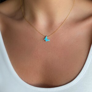 May include: A delicate gold chain necklace with a small blue opal butterfly pendant.