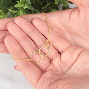 May include: A gold necklace with four interlocking circles. The necklace is delicate and dainty, and would make a great gift for a friend or loved one.