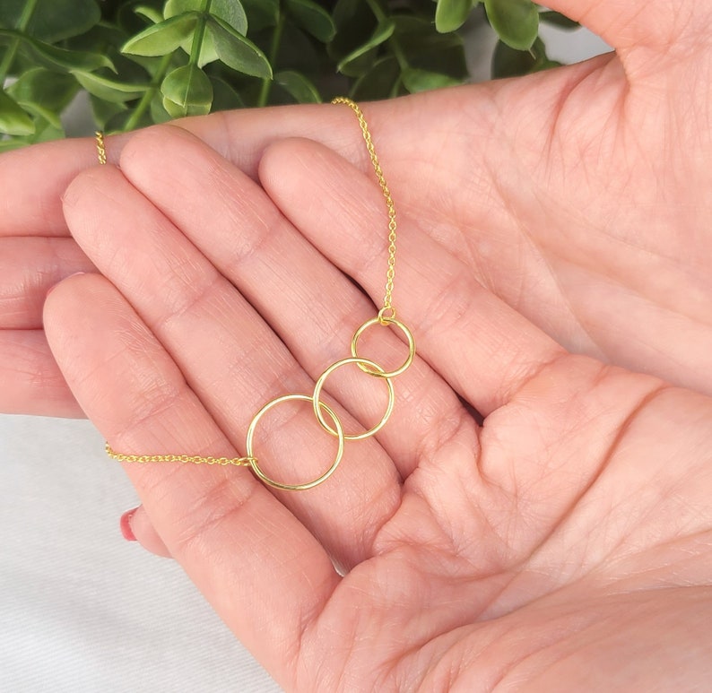May include: A gold necklace with four interlocking circles. The necklace is delicate and dainty, and would make a great gift for a friend or loved one.