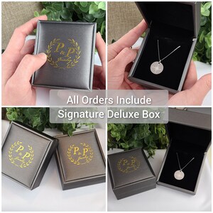 May include: A gray jewelry box with a gold logo that says "P&P Jewelry". The box is open and a silver necklace with a compass pendant is inside.