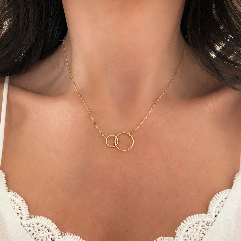 May include: A gold necklace with two interlocking circles as a pendant.