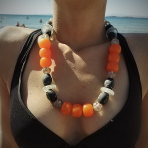 Collar de cuentas con faturan naranja, vidrio soplado transparente, cerámica negra y elementos de alpaca.