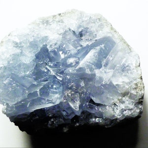 May include: A cluster of light blue celestite crystals in a natural formation. The crystals are translucent and have a glassy luster. The celestite is set in a matrix of gray rock.