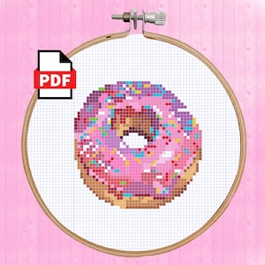 May include: A cross stitch pattern of a pink donut with purple and blue sprinkles. The pattern is in a hoop and is ready to be stitched.