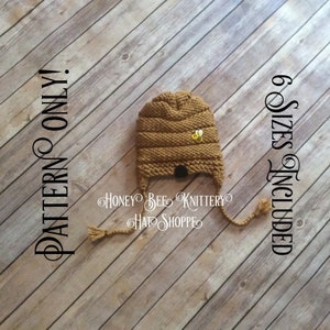 Puede incluir: Un gorro de punto marrón en forma de panal con una abeja amarilla aplicada. El gorro tiene una larga corbata y está sobre un fondo de madera. El texto "6 Sizes Included" está escrito verticalmente en el lado derecho de la imagen. El texto "PATTERN ONLY!" está escrito verticalmente en el lado izquierdo de la imagen.