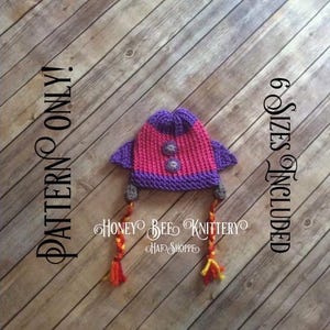 Könnte beinhalten: Eine gestrickte Raketenmütze in Lila und Pink mit gelben und orangen Garnzöpfen. Die Mütze befindet sich auf einem Holzgrund. Der Text "PATTERN ONLY" befindet sich auf der linken Seite des Bildes und "6 SIZES INCLUDED" auf der rechten Seite des Bildes. Der Text "Honey Bee Knittery" befindet sich unter der Mütze.