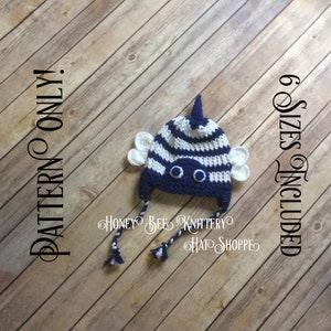 May include: Crochet bee hat pattern for babies in six sizes. The hat is white and navy blue with a striped pattern and bee wings. The pattern includes instructions for making the hat and the bee wings.