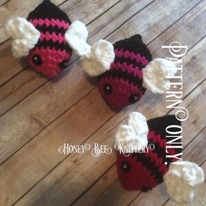 May include: Three handmade crochet bees with black, pink, and white details. The bees have black eyes and white wings. The text "PATTERN ONLY!" and "HONEY BEE KNITTERY" are visible.