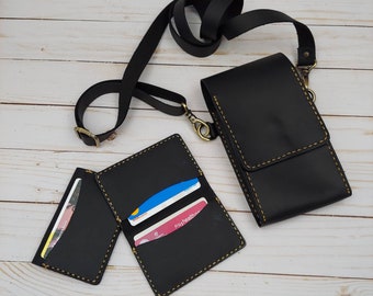 Puede incluir: Funda de teléfono de cuero negro con una correa desmontable y dos ranuras para tarjetas. La funda tiene costuras amarillas y un cierre de metal dorado.