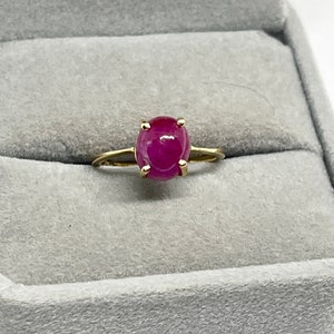 May include: A gold ring featuring a large oval ruby gemstone.