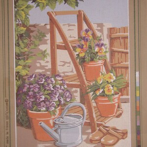 May include: A vintage needlepoint kit featuring a wooden ladder with three potted plants, a watering can, and gardening tools. The kit includes a printed canvas, yarn, and instructions. The kit is titled "L'escabeau fleuri" and is by the brand "DOUGLASILVER".