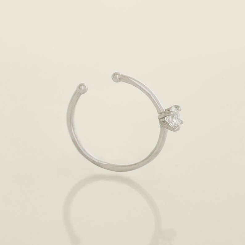 May include: A silver nose ring with a clear gemstone.