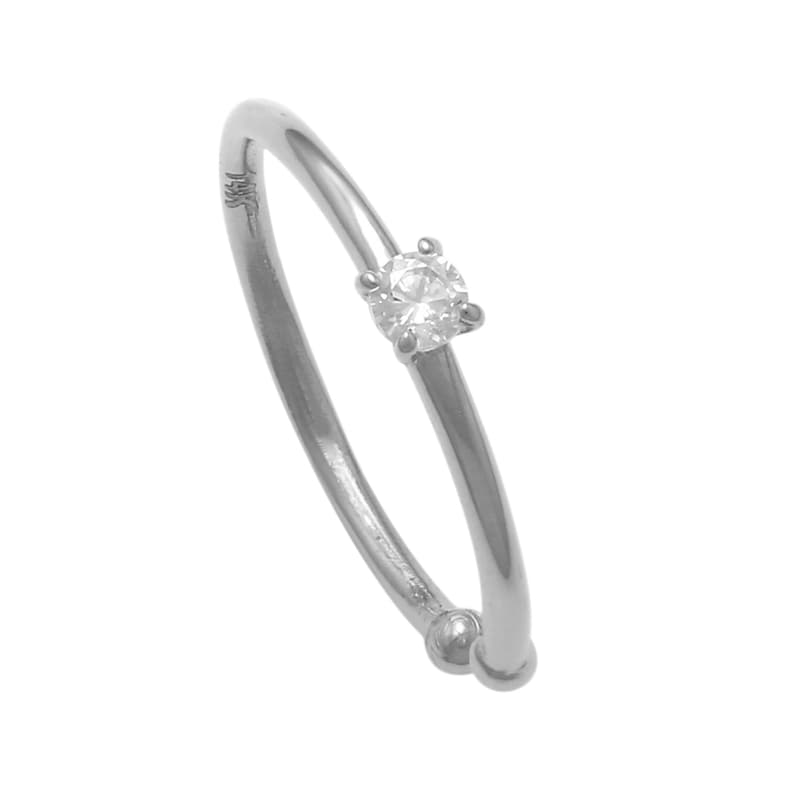 May include: A silver ring with a single clear round gemstone.