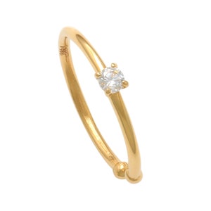 May include: A gold ring with a single clear gemstone.