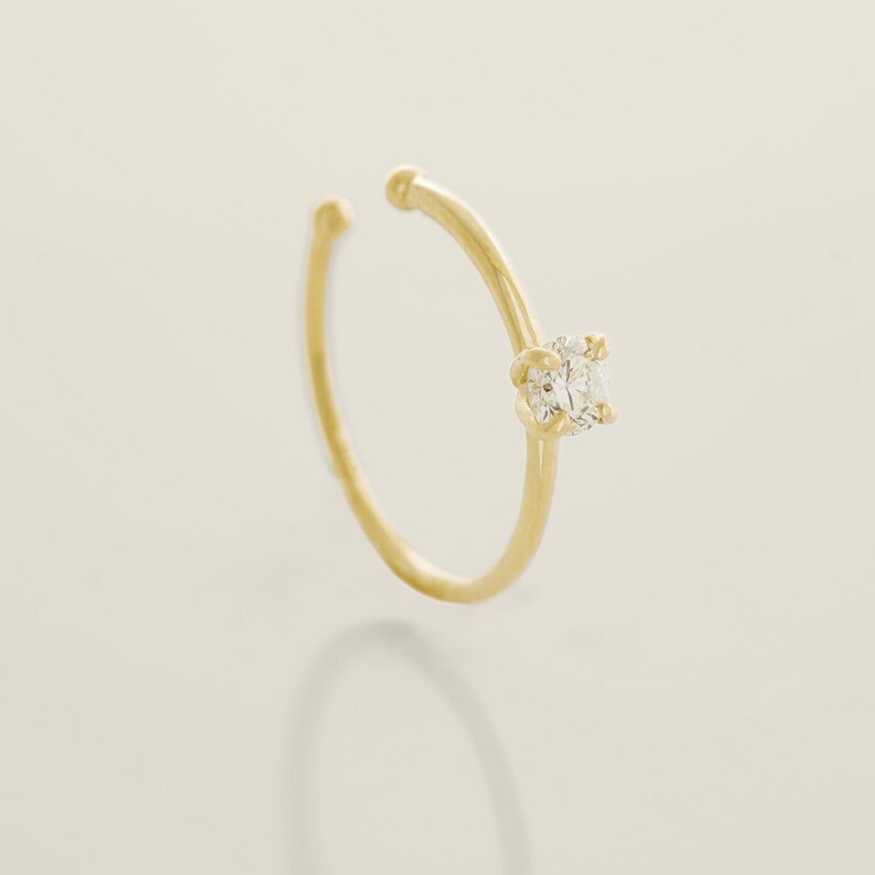 May include: A gold ear cuff with a single clear round gemstone.