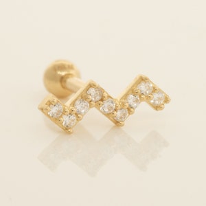 K&ouml;nnte beinhalten: Goldener Ohrstecker mit Zickzack-Design, besetzt mit klaren Zirkonia-Steinen.