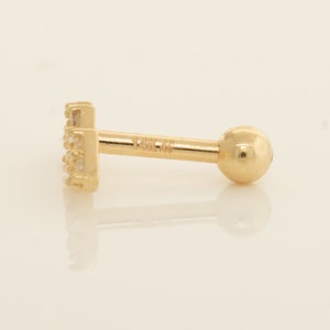 K&ouml;nnte beinhalten: Ein goldener Barren-Ohrstecker mit einer Reihe kleiner, klarer Zirkonia-Steine. Der Ohrstecker ist mit "14K 48" gekennzeichnet.