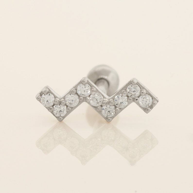 K&ouml;nnte beinhalten: Ein silberner Ohrring in Chevron-Form mit klaren Zirkonia-Steinen.