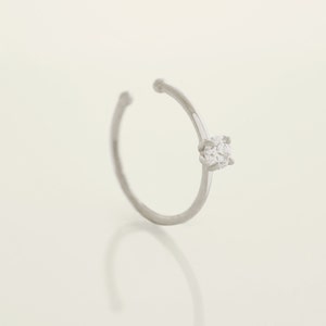 May include: A silver ear cuff with a single clear cubic zirconia stone.