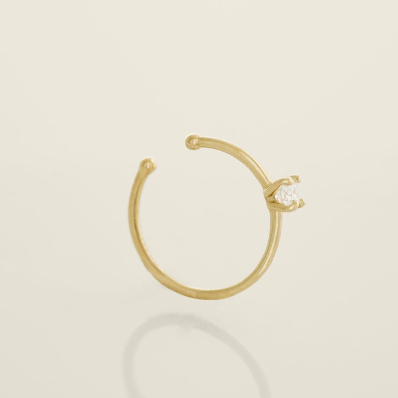 May include: A gold ear cuff with a single clear gemstone.