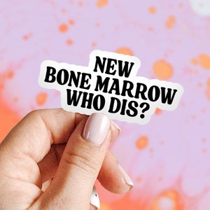 Op de afbeelding: Een witte sticker met zwarte tekst die "NEW BONE MARROW WHO DIS?" zegt. De sticker wordt vastgehouden door een hand tegen een roze en oranje achtergrond.