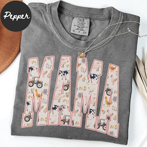 A gray t-shirt with the word "MAMA" printed on it, featuring various farm and animal-themed illustrations.