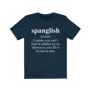 Puede incluir: Una camiseta azul marino con texto blanco que dice "spanglish (nombre) Cuando you can't find la palabra en un idioma so you fill it in con la otra."