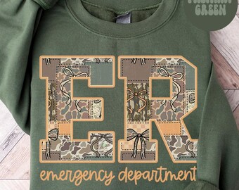 May include: Military green sweatshirt with the letters "ER" in a patchwork design. The letters are filled with camouflage and bow patterns. The words "emergency department" are printed below the letters.