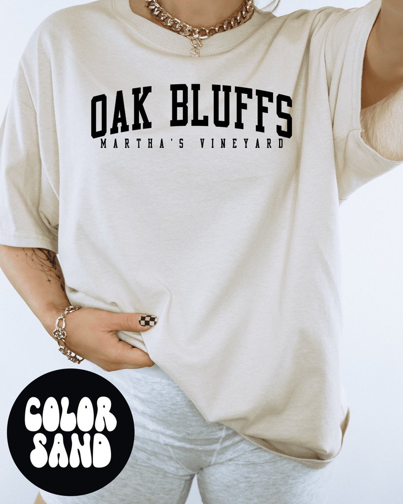 May include: A white t-shirt with black text that reads "OAK BLUFFS MARTHA'S VINEYARD". The shirt is oversized and has a relaxed fit.