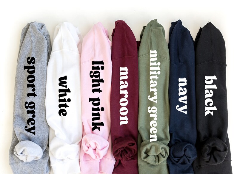 May include: Seven different colored sweatshirts with the color name printed on each in white text. The colors are sport grey, white, light pink, maroon, military green, navy, and black.