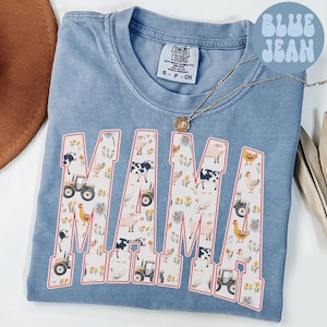 A blue t-shirt with the word "MAMA" printed on it, featuring various farm animals and farm-related elements.