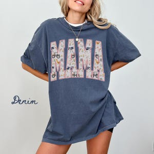 A woman wearing a blue t-shirt with the word "MAMA" printed on it.