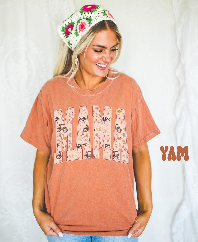 A smiling woman wearing a floral headband and a t-shirt with the word "MAM" printed on it.