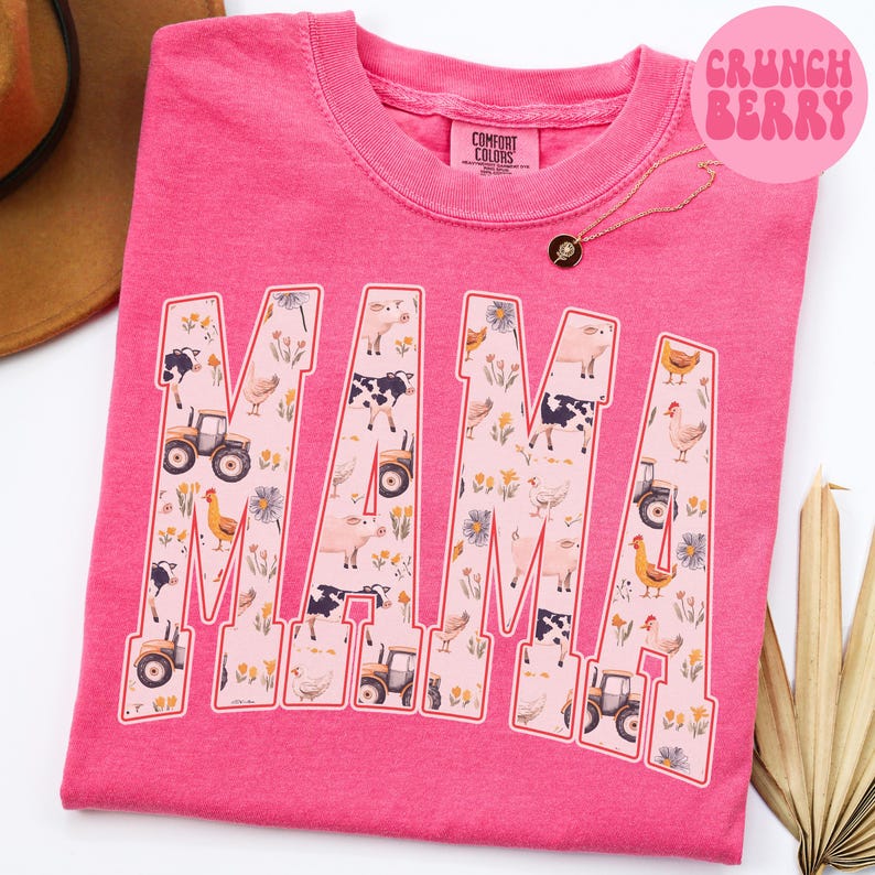 A pink t-shirt with the word "MAMA" printed on it, featuring various farm and animal-themed illustrations.