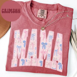A pink t-shirt with the word "MAMA" printed in large letters, along with a necklace and a brown hat.
