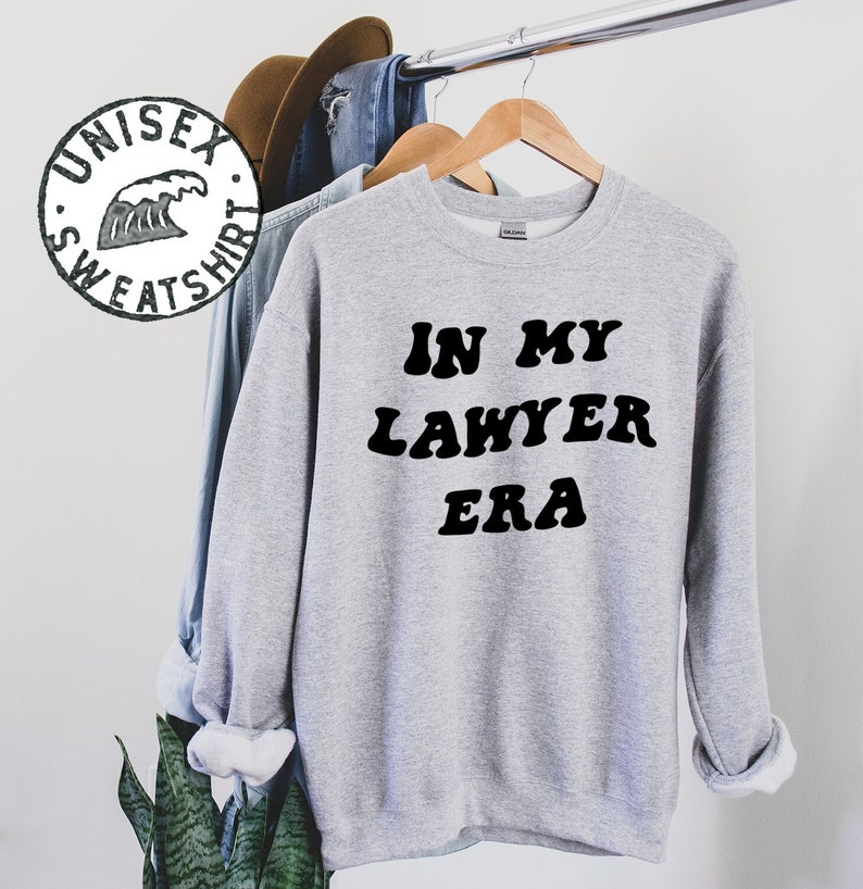 May include: Gray sweatshirt with the text "IN MY LAWYER ERA" in black retro-style lettering.